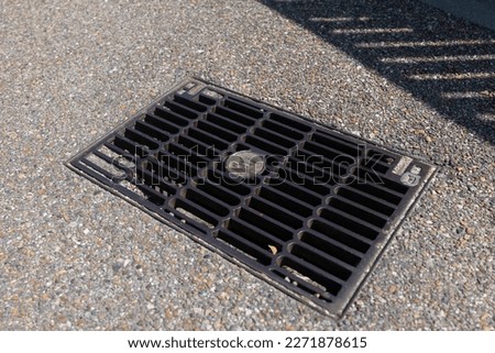 This stock photo showcases a drainage grate located on a roadway, designed to effectively drain rainwater and other waste.