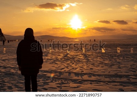 OLKHON, Baikal - February 22, 2023 : Amazing Baikal Lake ,Young adult woman's silhouette on lake on sunset sky,design for business,relax woman,freedom woman.