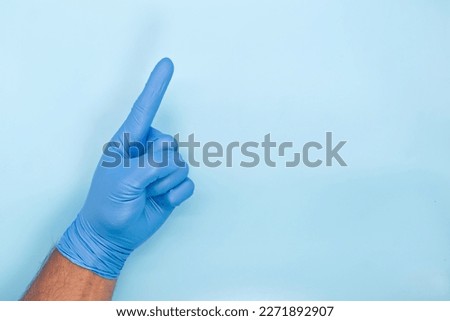 doctor hand in blue glove show number one on blue background.