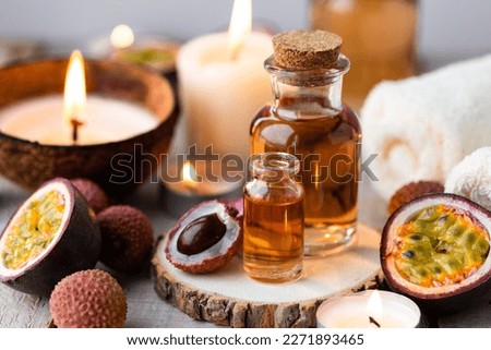Glass bottles with pure organic essential litchi and passion fruit oil on wooden background. Concept of natural ingredients for beauty treatment, skin care, massage. Exotic fruits extract and essence Royalty-Free Stock Photo #2271893465