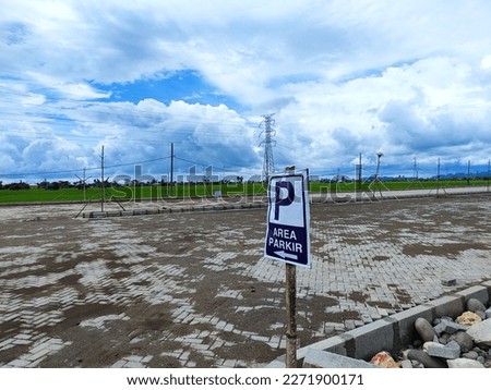 a very large parking lot which is next to the green grass and has a good view of the clouds