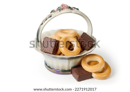 Bagels and chocolates in a porcelain vase. Vase with confectionery on a white background.