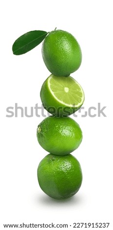 Stacked whole and cut limes on white background