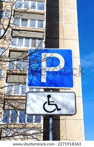 Next to the residential building there is a road sign parking for people with disabilities