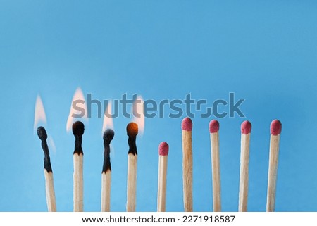 Burning and whole matches on light blue background, closeup. Stop destruction by breaking chain reaction concept Royalty-Free Stock Photo #2271918587