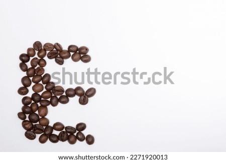 E is a capital letter of the English alphabet made up of natural roasted coffee beans that lie on a white background. Plenty of space to put text or pictures, top view and studio photography.