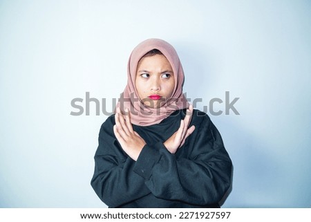 Beautiful annoyed Asian woman crossing hands makes stop gesture, demonstrates rejection isolated over white background