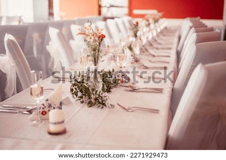 Decorated hall for wedding ceremony. Wedding. Banquet. The chairs and round table for guests, served with cutlery, flowers.