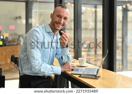 Friendly caucasian man in blue shirt showing mini heart hand sign and smiling to camera