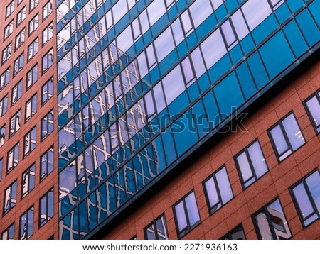 Part of a colorful facade of a commercial building in Frankfurt am Main, Germany, with many windows and the reflection of a neighboring high-rise
