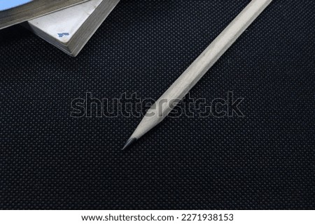 Pencils and book on a black background. Back to school, close-up. Education concept. Copy space.