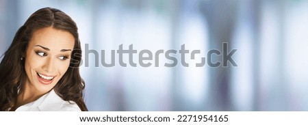 Happy excted smiling woman in white confident cloth looking aside. Business advertisement concept. Blurred modern office background. Brunette businesswoman, indoors. Royalty-Free Stock Photo #2271954165