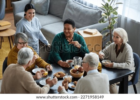 High angle view at group of senior people sitting at table together and smiling happily in retirement home Royalty-Free Stock Photo #2271958149