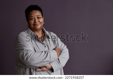 Minimal waist up portrait of black senior woman smiling at camera standing against purple background, copy space Royalty-Free Stock Photo #2271958257