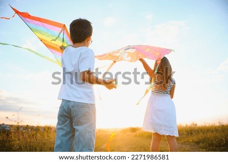 Children launch a kite in the field at sunset.