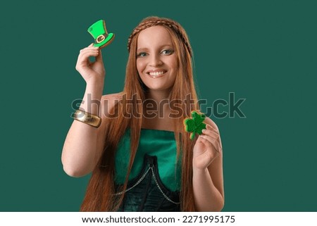 Beautiful redhead woman with cookies on green background. St. Patrick's Day celebration
