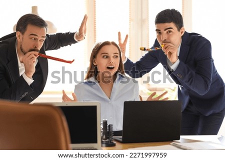 Young men with party blowers and their colleague in office. April Fools' Day celebration Royalty-Free Stock Photo #2271997959