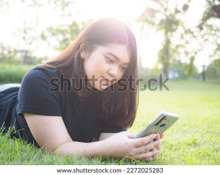 Portrait young woman asian chubby cute beautiful one person wear black shirt look hand holding using smart phone in garden park outdoor evening sunlight fresh smiling cheerful happy relax summer day