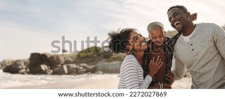 Smiling young man and woman with their son on the beach. Beautiful family on vacation at beach.