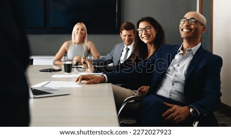 Group of diverse business people sitting in a boardroom, smiling and paying attention as they hear a presentation. Successful professionals having a meeting and working as a team in an office. Royalty-Free Stock Photo #2272027923