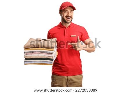 Laundry worker holding a pile of folded clothes and pointing isolated on a white background

