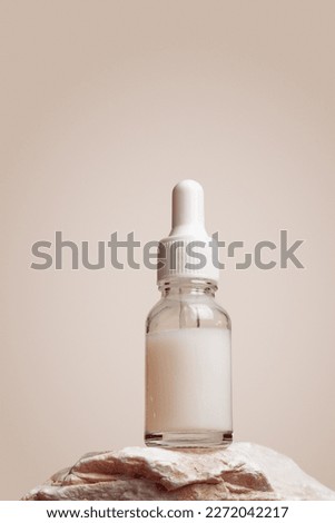 Glass dropper bottle with extract coconut or serum on stand from natural stones on beige background. Natural Organic Spa Cosmetic concept, cosmetic product mock up, minimal style. Side view, copyspace Royalty-Free Stock Photo #2272042217