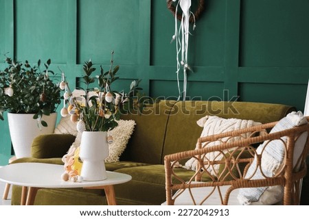 Vases with tulips, tree branches, Easter eggs and rabbits on table in living room