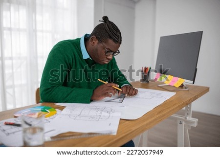 African American Architect Man Working Drawing A Plan Using Ruler Sitting At Workplace Near Computer Screen In Modern Office. Successful Design Career Concept. Side View Shot