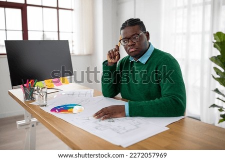 Thoughtful Black Engineer Man Working On Technical Drawing Thinking Holding Pencil At Workplace Indoors. Shot Of A Professional Architect Sitting At Desk In Modern Office