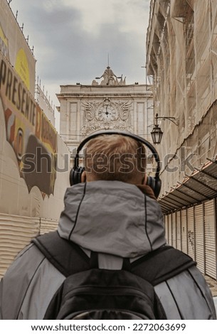 Rear View Of A Man With Headphones Contemplating A Historical Monument In Lisbon. Focus On The Background