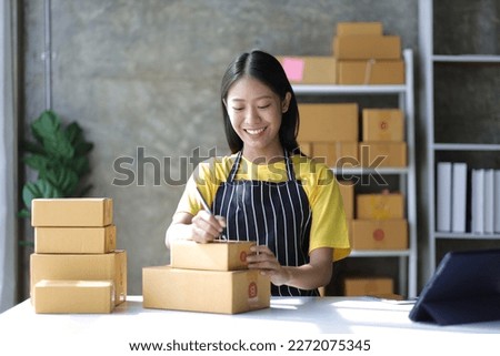 Young small business entrepreneur working with laptop and parcel boxes preparing for delivery.