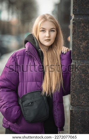 Portrait of a young beautiful fair-haired girl on a spring street.