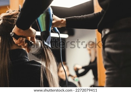 Master woman hairdresser dries the girl's hair with a hairdryer after washing in a beauty salon. Royalty-Free Stock Photo #2272079411