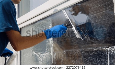 Male professional cleaning service worker in overalls cleans the windows and shop windows of a store with special equipment Royalty-Free Stock Photo #2272079415