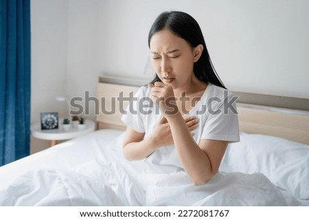 Asian woman feeling sick and coughing in bed in the morning. Respiratory diseases. Royalty-Free Stock Photo #2272081767