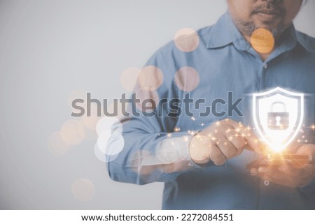Businessman use smartphones touching virtual icon shields with a lock symbol on hand on grey background with copy space. Protection against dangers and cyber security.