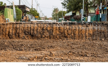 A low view from the ground to the cross section under paved roads that have been cut and renovated, common in the Thai countryside during the summer. Royalty-Free Stock Photo #2272089713