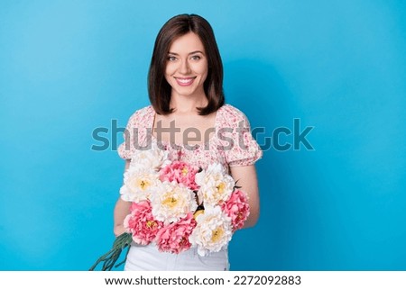 Photo portrait of cute young lady hold peony bouquet toothy smiling dressed trendy flower print garment isolated on blue color background