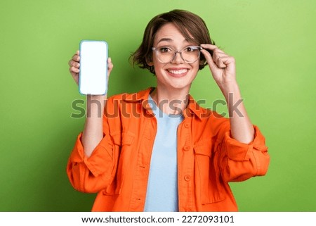 Photo of sweet shiny woman wear denim jacket spectacles showing modern device empty space isolated green color background
