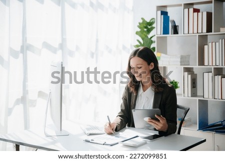 Woman freelancer is working her job on computer tablet and laptop Doing accounting analysis report real estate investment data, Financial at modern office Royalty-Free Stock Photo #2272099851