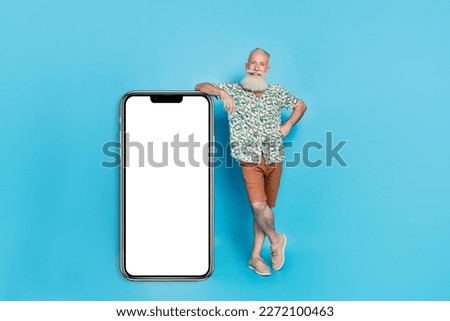 Full size portrait of handsome positive person stand near huge empty space telephone display isolated on blue color background
