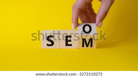 Seo and Sem symbol. Hand turns a cube and changes the word Sem to Seo. Beautiful yellow background. Businessman hand. Business and Seo and Sem concept. Copy space