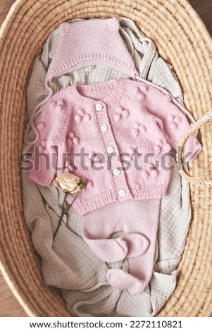Baby knitted clothes in wicker basket. Preparation for childbirth.