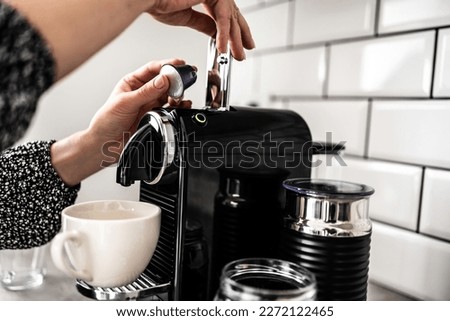 Girl hand put capsule to coffee machine closeup. Woman preparing italian caffeine beverage using professional espresso maker Royalty-Free Stock Photo #2272122465