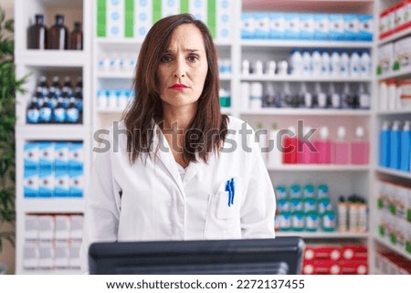 Middle age brunette woman working at pharmacy drugstore skeptic and nervous, frowning upset because of problem. negative person.  Royalty-Free Stock Photo #2272137455
