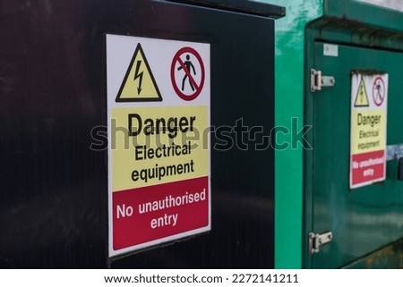 Danger electrical equipment and no unauthorised entry sign on black and green electric meter boxes, infrastructure and energy editorial illustration.