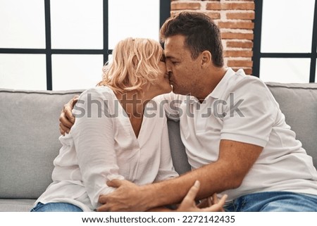 Middle age man and woman kissing and hugging each other at home