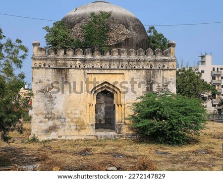 Stock photo of ancient ruined tomb monument placed middle of the city, few plants grows around the tomb. Picture captured under bright sunlight at Gulbarga, karnataka, India. historical place in India