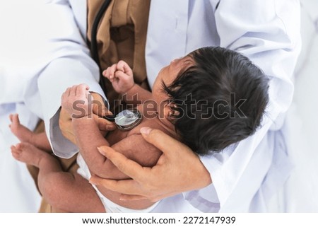 doctor woman using a stethoscope, checking the respiratory system and heartbeat of a 1-month-old baby newborn, who is half Nigeria half Thai, to Infant health care concept. Royalty-Free Stock Photo #2272147939