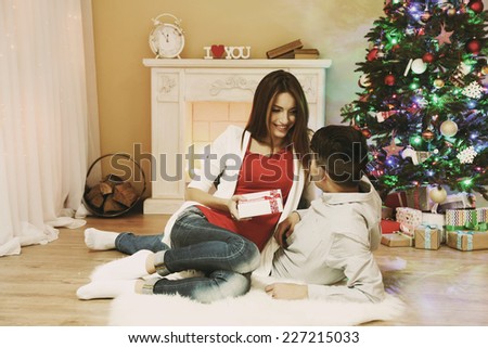 Young couple with gifts, sitting on carpet, at home